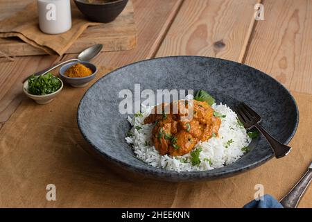 Oben serviert Huhn garam tikka masala auf dem Teller auf dem hölzernen Tischhintergrund Stockfoto