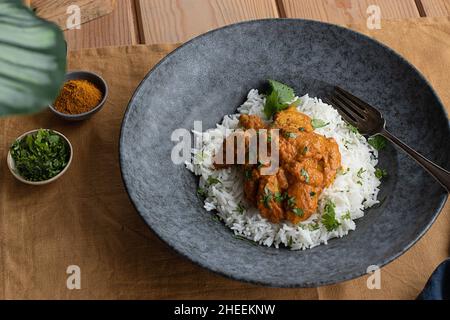 Oben serviert Huhn garam tikka masala auf dem Teller auf dem hölzernen Tischhintergrund Stockfoto