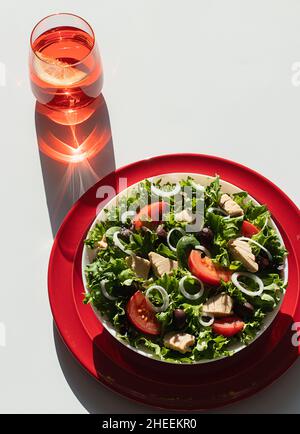Von oben Thunfischsalat mit Zwiebeln und Tomaten auf roten Tellern auf weißem Hintergrund serviert Stockfoto