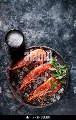 Hoher Garnelenwinkel in einer Schüssel mit Eis und Petersilie auf einem schwarzen Tisch im Luxusrestaurant Stockfoto