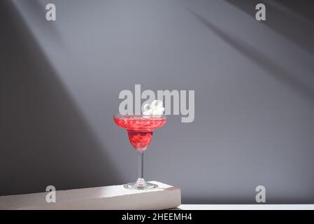 Kristallglas margarita Cocktail aus Granatapfel, serviert mit Blumenblüten auf Betonblöcken im Studio Stockfoto