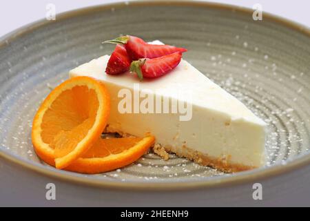 Käsekuchen mit Erdbeere und Orange bei der Nahaufnahme des Tellers. Stockfoto