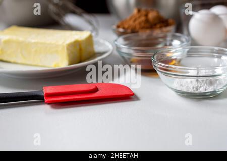 Seitenansicht der Backzutaten. Zu den Zutaten gehören: Ei, Butter, Vanille, Kakao und Backpulver. Stockfoto