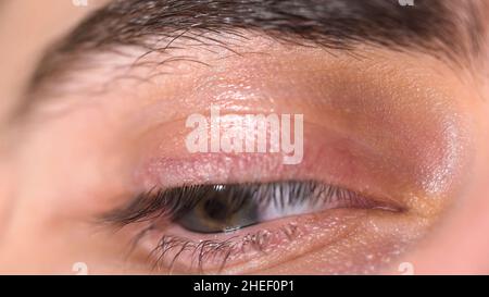 Extreme Nahaufnahme eines wunderschönen blauen Männerauges, das sich umsieht, menschliches Körperkonzept. Bewegung des blauen männlichen Auges. Stockfoto
