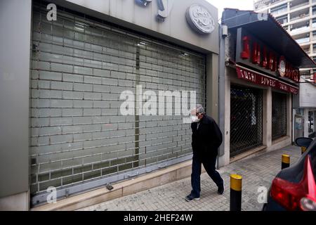 Beirut, Libanon. 10th Januar 2022. Ein Mann geht am 10. Januar 2022 an einem geschlossenen Geschäft in Beirut, Libanon, vorbei. Libanesische Händler wurden 2021 von der beispiellosen Wirtschafts- und Finanzkrise des Landes getroffen, bei der laut der Beirut Traders Association 35 Prozent von ihnen ihre Geschäfte oder einige Filialen schlossen. Quelle: Bilal Jawich/Xinhua/Alamy Live News Stockfoto