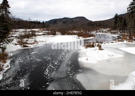 Ein Blick auf den Kunjamuk River in den Adirondack Mountains im Winter mit Schnee und Eis auf dem Wasser. Stockfoto