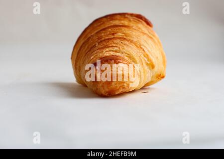 Frisch gebackenes Croissant auf einem Pergamentpapier. Fertig zum Blätterteig Backen. Herzhaftes und hausgemachtes Bäckerkonzept. Stockfoto