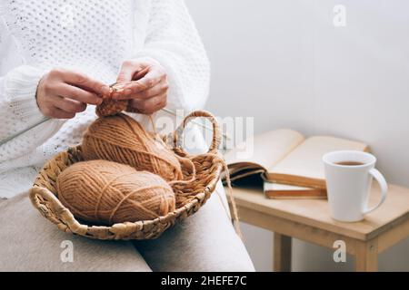 Eine Frau mittleren Alters beschäftigt sich mit häuslicher Handarbeit Stricken, Stricken mit Fäden. Home-Aktivität Hobby in der Freizeit Stockfoto