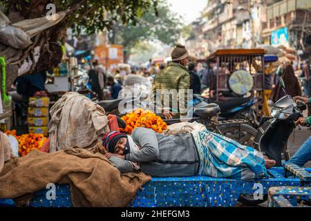 Neu-Delhi, Indien. 10th Januar 2022. Ein Arbeiter wird während seiner Arbeitszeit auf seinem hölzernen Handwagen schlafen sehen. Weniger Arbeit auf dem Markt aufgrund von Covid19, auf Chandni Chowk Market, Geschäfte dürfen nur auf ungerader Basis öffnen (ungerade-gerade Regelung ist ein Rationierungssystem) zwischen 10 und 8 Uhr inmitten der dritten Welle von Coronavirus in Delhi. Kredit: SOPA Images Limited/Alamy Live Nachrichten Stockfoto