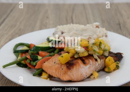 Reichhaltiges Protein in diesem herzhaften gegrillten Lachsfilet, serviert mit Kartoffelpüree und gemischtem Gemüse. Stockfoto