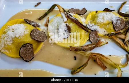 Italienische Küche, frisch hausgemachte rote Kartoffel gefüllte Pasta Tortellacci oder Ravioli Knödel mit Sommer schwarzen Trüffel und knusprigen grünen Spargel und geriebt Stockfoto