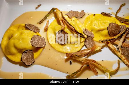 Italienische Küche, frisch hausgemachte rote Kartoffel gefüllte Pasta Tortellacci oder Ravioli Knödel mit sommerlichen schwarzen Trüffeln und knusprigen grünen Spargel, Parma, E Stockfoto