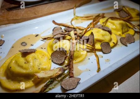 Italienische Küche, frisch hausgemachte rote Kartoffel gefüllte Pasta Tortellacci oder Ravioli Knödel mit sommerlichen schwarzen Trüffeln und knusprigen grünen Spargel, Parma, E Stockfoto