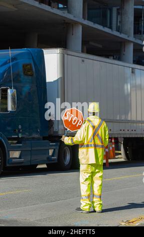 Ein Bauarbeiter, der den Verkehr stoppt, hält ein Stoppschild – 22,2020. Oktober – White Rock BC, Kanada. Straßenansicht, selektiver Fokus. Stockfoto