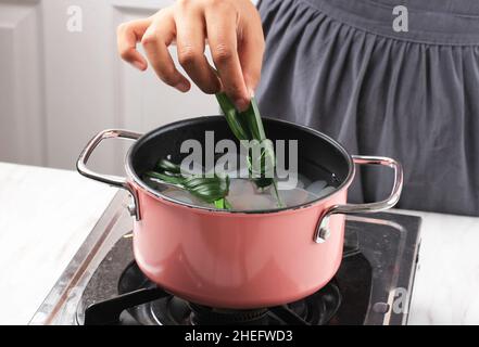 Legen Sie Pandan Blatt auf eine rosa Pfanne enthalten Zucker Palme Frucht (Kolang Kaling). Kochvorgang Herstellung von Manisan Cangkaleng für Ramadhan Frühstück Takjil Stockfoto