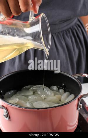 Nahaufnahme Einfache Sirup oder Zuckersirup oder flüssiger Zucker in die Pfanne geben, wobei Manisan Kolang Kaling (Sugar Palm Fruit) für Ramadan oder IED Fitr verarbeitet wird Stockfoto