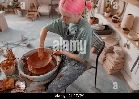 Junger Töpfer, der Ton mit Instrument im Kunststudio formt Stockfoto