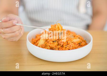 Eine Frau schaufelt ihren hausgemachten Kimchi-gebratenen Reis. Stockfoto