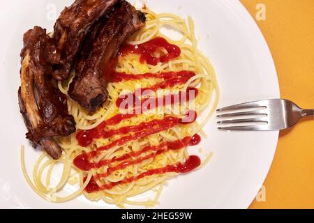 Süsse Schweinerippchen mit Spaghetti auf dem Esstisch. Hintergründe zu Lebensmitteln Stockfoto