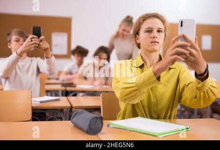 Klassenkameraden nutzen ihre Smartphones während des Unterrichts stark Stockfoto