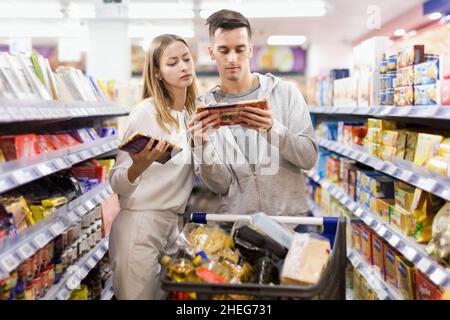 Junge positive Kunden, die Schokolade in Lebensmitteln wählen de Stockfoto