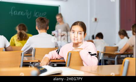 Trauriges junges Schulmädchen, das während des Unterrichts die Kamera anschaut Stockfoto