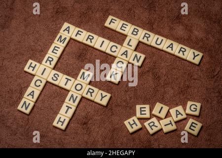 Februar - African American (oder Black) History Month Kreuzworträtsel in Elfenbein Buchstaben Fliesen gegen strukturierte handgemachte Papier, jährliche Einhaltung Ursprung Stockfoto