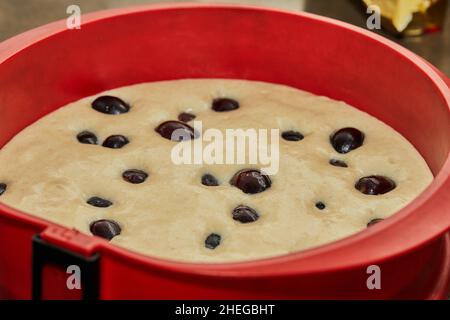 Silikonform mit Teig und Trauben für Kuchen in der Küche vor dem Backen Stockfoto