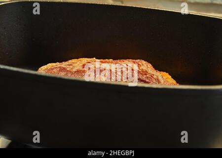 Großes Stück Rindfleisch wird in einem speziellen Kessel auf einem Gasherd gebraten Stockfoto