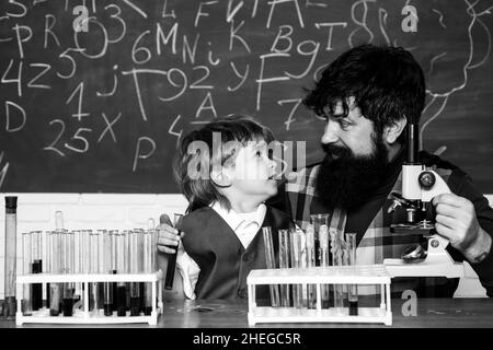 Bildung und Lernen Menschen Konzept - kleiner Student Junge und Lehrer. Wissenschaft. Lehrer, der Kindern bei ihren Hausaufgaben im Klassenzimmer in der Schule hilft. Stockfoto