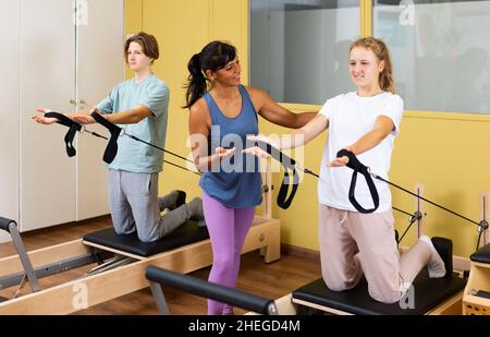 Kleiner Junge und Mädchen mit Pilates-Trainer im Fitnessstudio Stockfoto