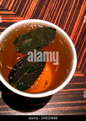 Kräutertee in einer Papiertasse mit Blättern aus Feuerkraut. Blick von oben. Stockfoto