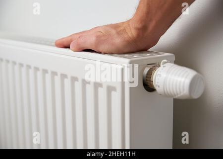 Die Temperatur am Heizkörper-Thermostat von Hand einstellen und den Heizkörper-Regler drehen, um die Wärme zu Hause zu steuern Stockfoto
