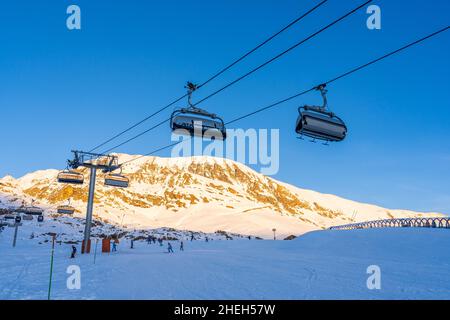 Alpe d'Huez, Frankreich - 30.12.2021 : Skiliftseilbahn am Abend auf alpinem Bergwintergebiet. Ski Sessellift Seilbahn mit Menschen. Typisch fren Stockfoto