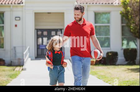 Vater unterstützt und motiviert Sohn. Kind geht zur Grundschule. Lehrertag. Stockfoto