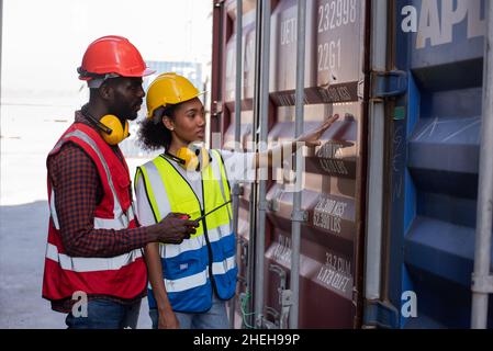 Junge afroamerikanische Arbeiter kontrollieren und kontrollieren die Verladung von Frachtcontainern. Stockfoto