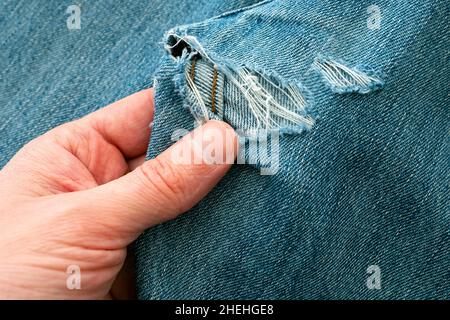 Mann erkunden Loch in zerrissene Jeans, bevor sie nähen Stockfoto