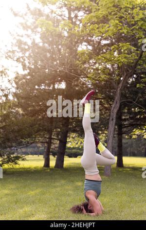 Junge Frau praktiziert Yoga im öffentlichen Park bei Sonnenaufgang Stockfoto