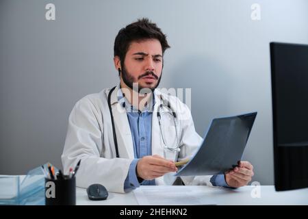 Der junge Arzt schaute erstaunt auf die Röntgenaufnahme eines Beckens und einer Wirbelsäule. Stockfoto