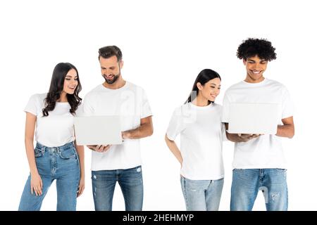 Erfreut interracial Männer mit Laptops in der Nähe von jungen Frauen isoliert auf weiß Stockfoto