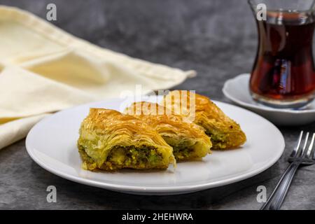 Pistazien-Baklava (Sobiyet) auf dunklem Hintergrund. Traditionelle türkische Küche Delikatessen. Nahaufnahme. Stockfoto