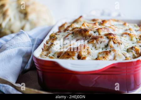 Köstliche hausgemachte Tortellini-Nudelauflauf mit gehackter frischer Petersilie und geschmolzenem goldenen Mozzarella-Käse. Selektiver Fokus mit Unschärfe Stockfoto