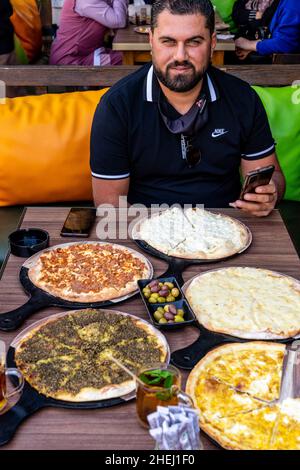Ein jordanischer Mann, der ein traditionelles Frühstück mit Fladenbrot isst, Aqaba, Aqaba Governorate, Jordanien. Stockfoto