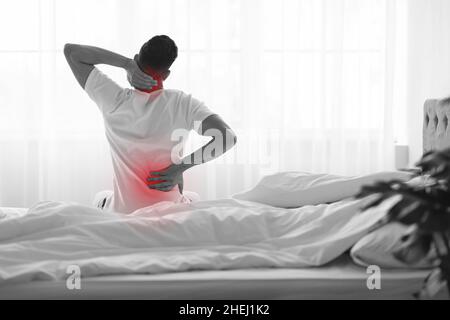 Unkenntlich Mann Reibt Schmerzhaften Rücken Und Nacken Nach Dem Aufwachen Am Morgen Stockfoto
