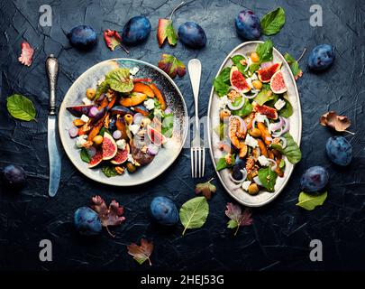 Herbstsalat mit Pflaumen, Feigen, Oliven und Käse. Salat der Saison mit Früchten und Nüssen Stockfoto