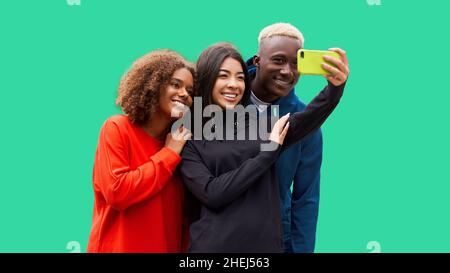 Studioaufnahme von netten jungen multikulturellen Freunden. Schöne Menschen fröhlich lächeln und Spaß haben, während Selfie-Foto zu machen. Isolierter grüner Hintergrund Stockfoto