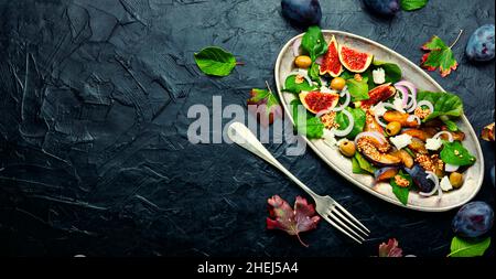 Herbstsalat mit Pflaumen, Feigen, Oliven und Käse.Salat der Saison mit Früchten und Nüssen.Platz für Text Stockfoto