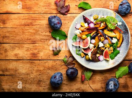 Herbstsalat mit Pflaumen, Feigen, Oliven und Käse.Salat der Saison mit Früchten und Nüssen.Platz für Text Stockfoto