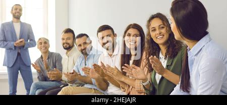 Glückliches Geschäftsteam, das ihrer Kollegin Anerkennung für ihre Arbeit zollt Stockfoto