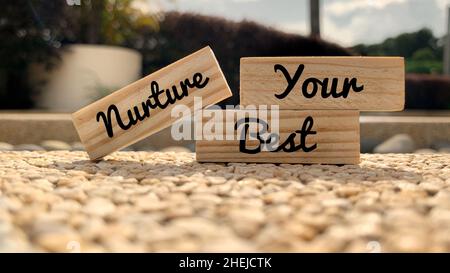 Text auf Holzblöcken - Nurture your Best. Mit unscharfem Parkhintergrund. Motivationskonzept. Stockfoto